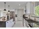 Modern kitchen with stainless steel appliances, a large island, stylish pendant lighting and white cabinets at 7684 S Ingalls St, Littleton, CO 80128