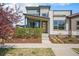 Modern two-story home with light brick accents, lush landscaping, and a bright yellow front door at 9051 E 61St Ave, Denver, CO 80238