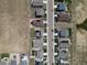 An aerial view shows a suburban neighborhood with manicured lawns and houses adjacent to an open field at 7414 Blue River Ave, Frederick, CO 80530