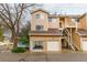 Inviting tan townhome featuring a two-car garage, exterior staircase, and well-maintained landscaping at 4713 Spine Rd # D, Boulder, CO 80301