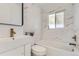 Stylish bathroom features marble-look tile, bathtub, a white vanity, and bronze fixtures at 2582 S Birch St, Denver, CO 80222