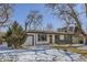 Single-story home with an attached garage, contrasted by the snow-covered yard and bare trees at 2582 S Birch St, Denver, CO 80222