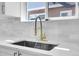 Close up of a well lit kitchen sink featuring high end fixtures and stone countertops at 1317 Monroe St, Denver, CO 80206