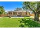 Brick home with a lush backyard, featuring a patio with chairs and a large tree for shade at 4685 Wadsworth Blvd, Wheat Ridge, CO 80033