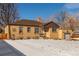 Quaint brick home with an attached single car garage and mature trees in winter setting at 4685 Wadsworth Blvd, Wheat Ridge, CO 80033