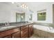 A Primary bathroom features double vanities, large mirror, and a soaking tub by a window at 5074 Yosemite Ct # 1, Denver, CO 80238
