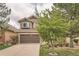 Charming exterior showcasing a two-car garage, stone accents, and lush landscaping at 9825 S Iris Ct, Littleton, CO 80127