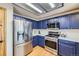 Bright kitchen featuring stainless steel appliances and blue cabinets at 11218 Newark Ct, Commerce City, CO 80640