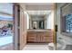 Bathroom featuring dual sink granite countertop vanity, stone accent wall, and direct access to indoor pool at 28 Indian Paintbrush Dr, Golden, CO 80401