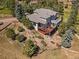 Aerial view showcases a two-story house, large deck, and intricate landscaping with walking paths at 31518 Niakwa Rd, Evergreen, CO 80439