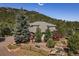 Back aerial view showcases landscaped gardens, deck, walking path, a fence and mature trees at 31518 Niakwa Rd, Evergreen, CO 80439