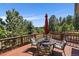 Inviting back deck area with outdoor seating, red umbrella, and scenic wooded views at 31518 Niakwa Rd, Evergreen, CO 80439