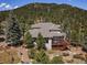 Beautiful exterior boasts large deck and a well-maintained garden, set against a backdrop of lush trees at 31518 Niakwa Rd, Evergreen, CO 80439