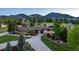 Aerial view of the home with an extended driveway and mature trees with lush green landscape at 5727 Colorow Dr, Morrison, CO 80465