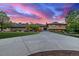 Beautiful tan and brick house with large driveway and manicured lawn under a stunning pink sunset at 5727 Colorow Dr, Morrison, CO 80465