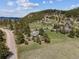 Aerial view of a property with lush trees, a charming home, and scenic mountain backdrop at 30651 Hollings Way, Golden, CO 80403