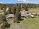 Aerial shot of a property featuring multiple buildings, set against a backdrop of trees and mountains at 30651 Hollings Way, Golden, CO 80403