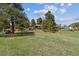 Large backyard featuring mature trees and a charming home with a deck and additional outbuildings at 30651 Hollings Way, Golden, CO 80403