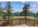 Expansive deck overlooking a lush meadow and distant mountain views under a sunny, partly cloudy sky at 30651 Hollings Way, Golden, CO 80403