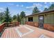 Back exterior featuring a wooden deck and stone accents, surrounded by lush trees at 30651 Hollings Way, Golden, CO 80403