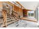 Bright sun room with a wood paneled wall, stone accent wall, and adjacent sitting area at 30651 Hollings Way, Golden, CO 80403