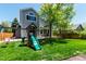 Spacious backyard featuring a modern playset surrounded by lush green lawn and mature trees at 10765 Fremont Dr, Parker, CO 80134