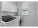 Well-lit laundry room with front-load washer, dryer, white cabinets, and neutral paint at 10765 Fremont Dr, Parker, CO 80134