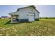 Spacious barn with a large roll-up door and a covered area on a property with verdant grass at 56920 E 42Nd Ct, Strasburg, CO 80136