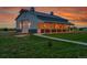 Large barn with metal roof, sliding garage door, and covered side porch with outdoor lighting at 56920 E 42Nd Ct, Strasburg, CO 80136
