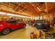 Spacious garage featuring a car lift, multiple vehicles, and ample storage space on wooden shelves at 56920 E 42Nd Ct, Strasburg, CO 80136