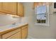 Functional laundry area with a sink, wooden cabinets, and a window providing natural light at 56920 E 42Nd Ct, Strasburg, CO 80136