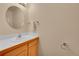 Simple powder room with a single sink, wooden vanity, and round mirror at 56920 E 42Nd Ct, Strasburg, CO 80136