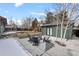 Charming backyard with patio seating area, landscaping, a detached garage, and partial winter snow coverage at 2490 S Coors St, Lakewood, CO 80228