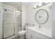 This simple bathroom features a glass shower, a classic round mirror, and a neutral toilet at 6376 E Mississippi Ave, Denver, CO 80224