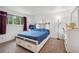 Bright bedroom features a plush blue quilted bed, sleek white furniture, and natural light from the window at 6376 E Mississippi Ave, Denver, CO 80224