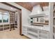 Open kitchen with brick ceiling, white cabinetry, a marble countertop, and a view into a large pantry with ladder at 1525 W 141St Way, Westminster, CO 80023
