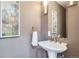 Stylish half bathroom with a pedestal sink, framed mirror, and decorative artwork at 222 S Monroe St, Denver, CO 80209