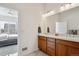 Bright bathroom featuring a double sink vanity with a view into the primary bedroom at 22046 E Allenspark Pl, Aurora, CO 80016