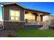 Inviting home with a covered patio and stone accents, surrounded by a green artificial lawn at 22046 E Allenspark Pl, Aurora, CO 80016