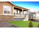 Charming home with a stone facade and a covered porch and green artificial lawn at 22046 E Allenspark Pl, Aurora, CO 80016