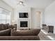 Bright living room features a cozy fireplace with a TV, ceiling fan, and comfortable brown sofa at 22046 E Allenspark Pl, Aurora, CO 80016