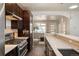 Well-lit kitchen featuring stainless steel appliances, dark wood cabinets and tiled backsplash at 2957 Osceola St, Denver, CO 80212