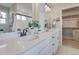 Modern bathroom with double sink vanity, sleek fixtures, and access to a walk-in closet at 1218 Sugarloaf Ln, Erie, CO 80516