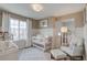 Bright Bedroom featuring a white crib, chair with ottoman, rug, and natural light from a large window at 1218 Sugarloaf Ln, Erie, CO 80516