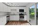 Modern kitchen featuring white cabinets, granite countertops, stainless appliances, and wood-look floors at 11823 Steele St, Thornton, CO 80233