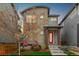 Modern home boasts a unique facade with a striking red door, complemented by mature landscaping and two red chairs at 6777 Larsh Dr, Denver, CO 80221