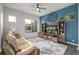 Stylish living room featuring blue accent wall, a ceiling fan, and comfortable leather sofa at 6777 Larsh Dr, Denver, CO 80221