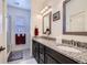 Bathroom featuring double sinks with granite counters, dark cabinets, and tiled floors at 15226 W 93Rd Ave, Arvada, CO 80007
