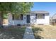 Charming single-story home with gray siding, black door, and tidy front yard landscaping under a clear blue sky at 7111 Clermont St, Commerce City, CO 80022