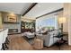 Spacious living room with a stone fireplace, wood beam accents, and large windows showcasing scenic views at 10826 Evergold Way, Highlands Ranch, CO 80126